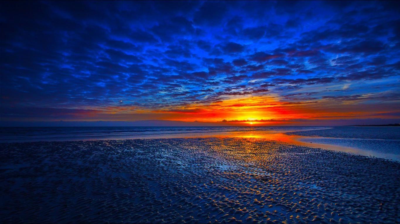 A serene sunset over a lake surrounded by trees, reflecting colorful skies.