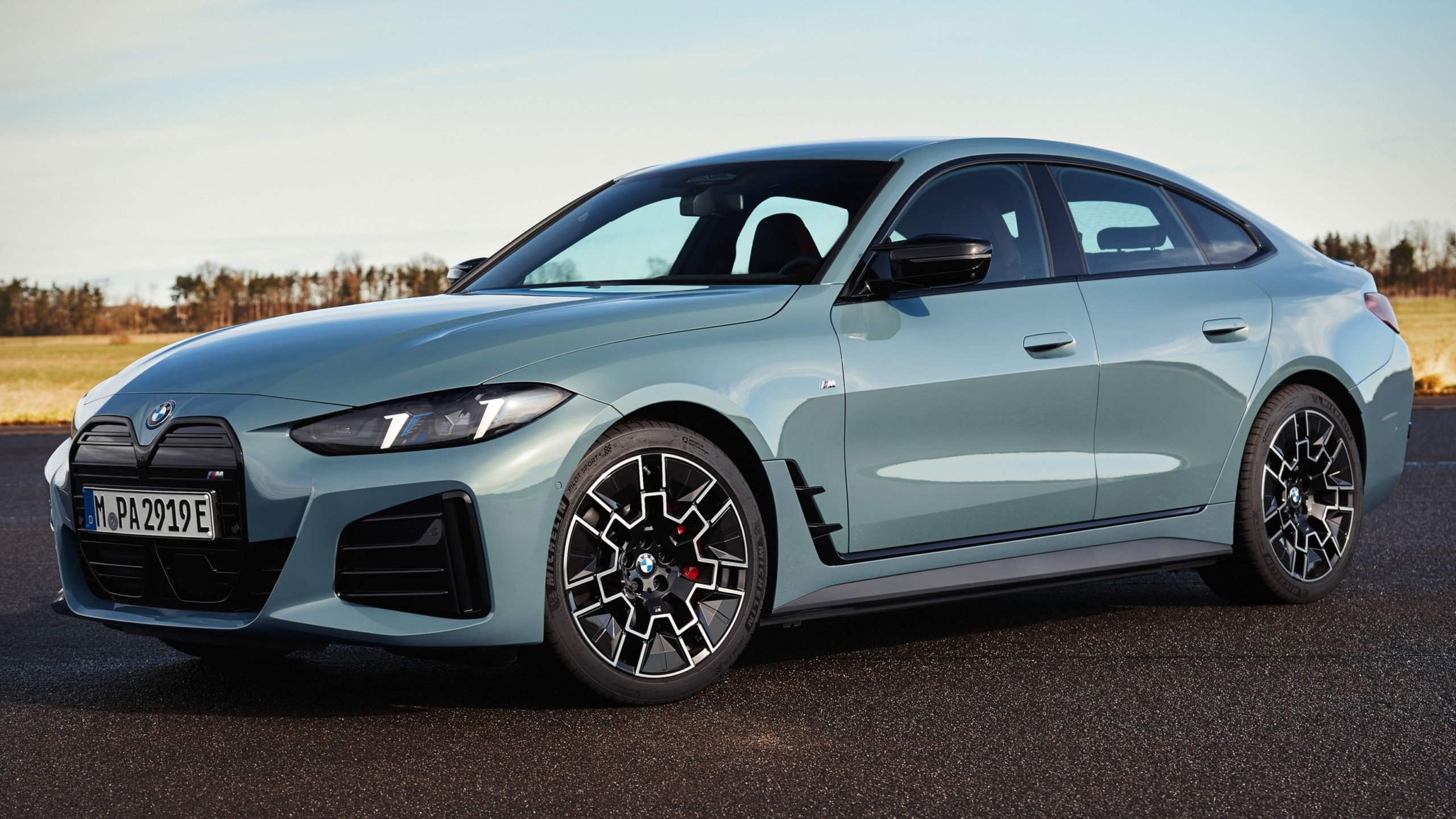 A modern BMW i4 electric sedan showcased in a futuristic urban setting, highlighting its design and the transition towards sustainable vehicles.